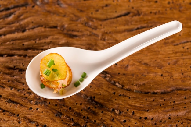 Foto mille foglie di patate dolci, tonno affumicato e cetrioli sottaceti in un cucchiaio. assaggia il fingerfood della gastronomia