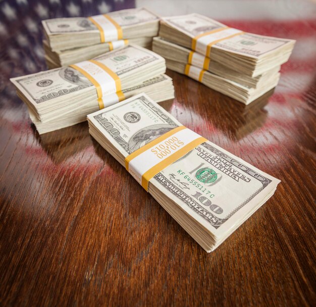 Photo thousands of dollars stacked with reflection of american flag on wooden table