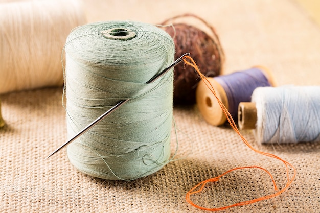 Thread spool with needle with other spools on canvas