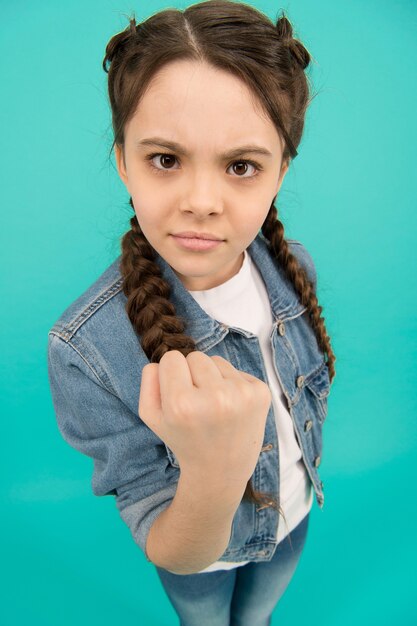 Threatening with fist. Angry child shake fist grey background. Beauty look of child girl. Small child in casual wear. Fashion style. Child care and childhood. International childrens day.