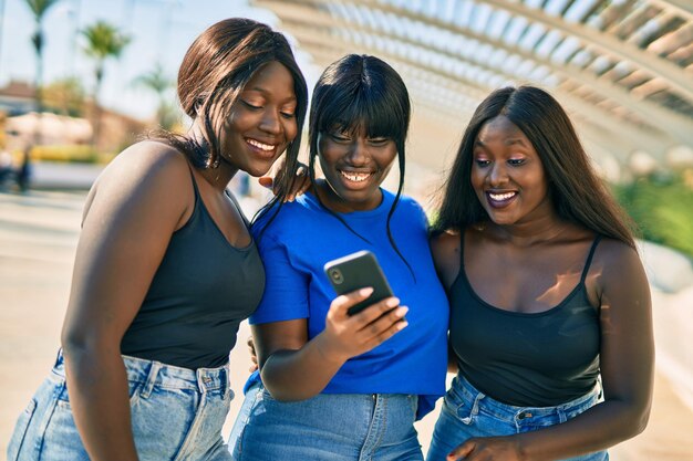 Photo three african american friends smiling happy using smartphone at the city