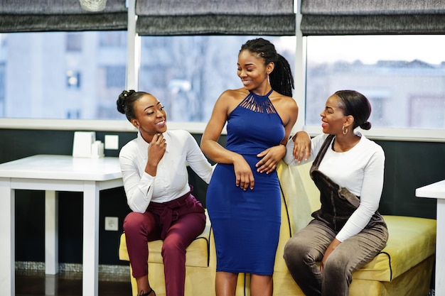 Three african woman in dress posing at restaurant