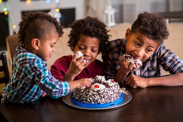 ケーキを食べる3人のアフロの男の子。