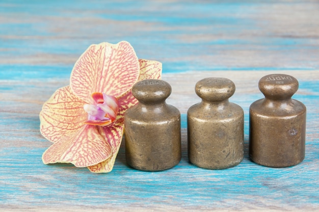 Three antique bronze weights for scales on blue wooden background. Copy space for text and food photography props.