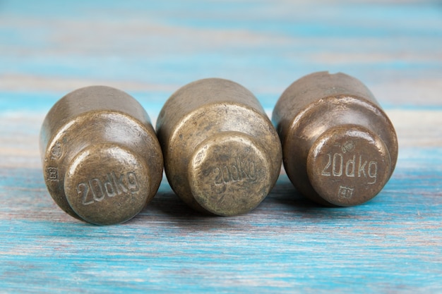 Three antique bronze weights for scales on blue wooden background. Copy space for text and food photography props.