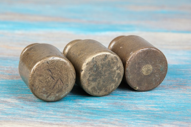 Three antique bronze weights for scales on blue wooden background. Copy space for text and food photography props.