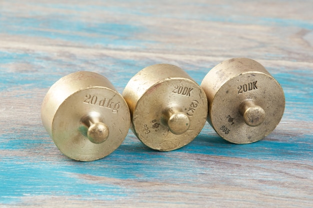 Three antique bronze weights for scales on blue wooden background. Copy space for text and food photography props.