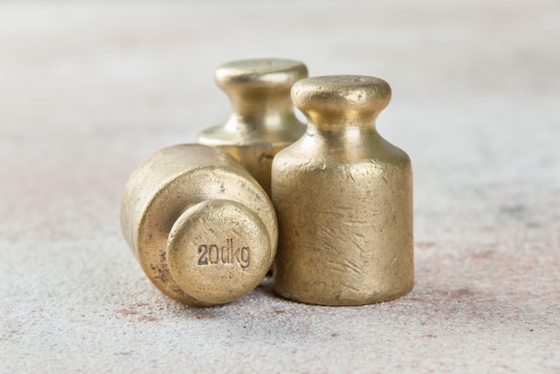 Three antique bronze weights for scales on concrete.