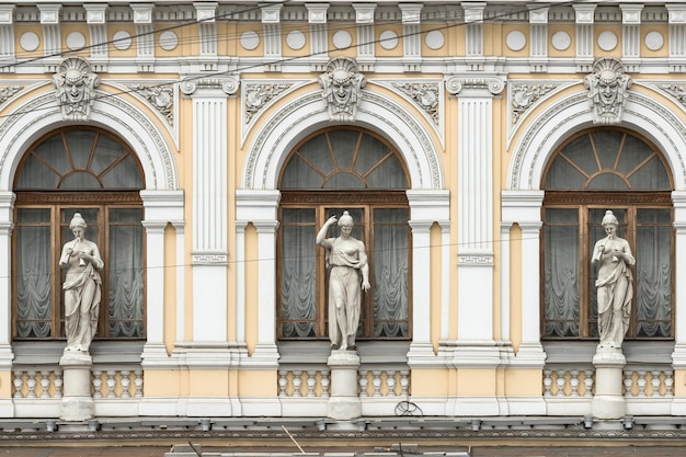 Three antique figures of women against the background of the windows of an old historical building