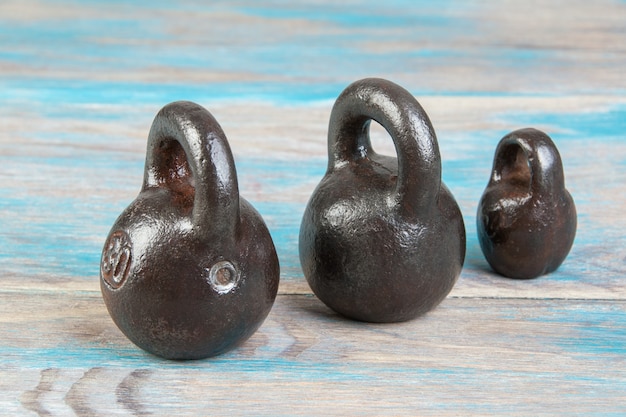 Three antique iron weights for scales on blue wooden background. copy space for text and food photography props.