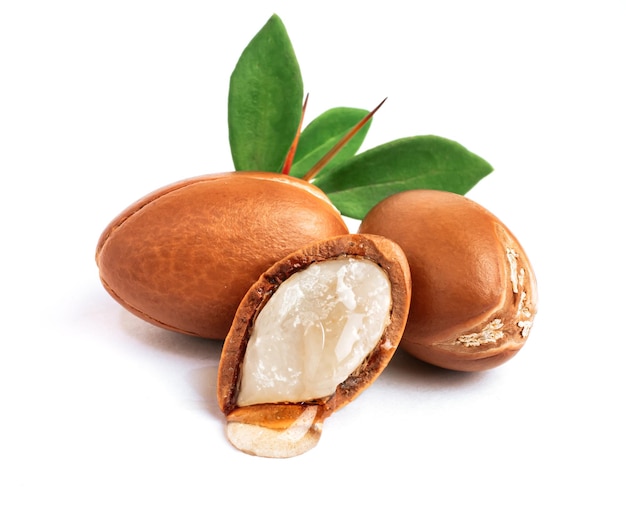 Photo three argan nuts with green leaves on an isolated white background