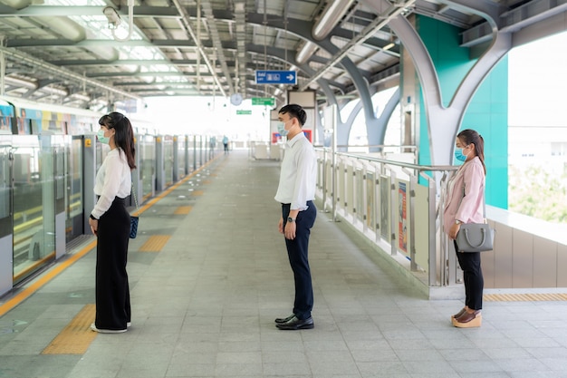 Three Asian people wearing mask standing distance of 1 meter from other people keep distance protect from COVID-19 viruses and people social distancing