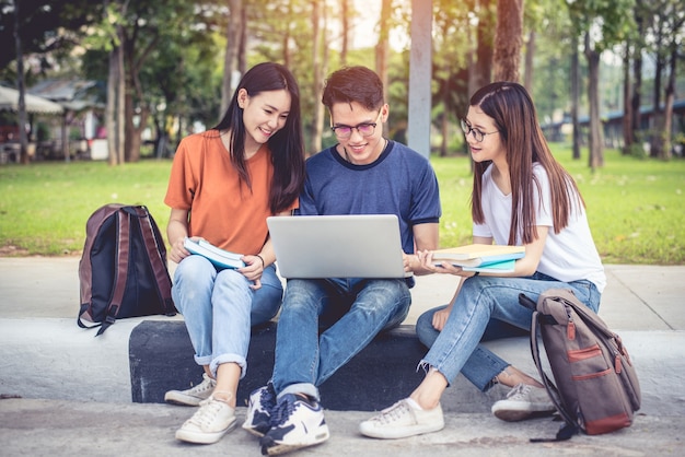 Three Asian young campus students enjoy tutoring and reading books together