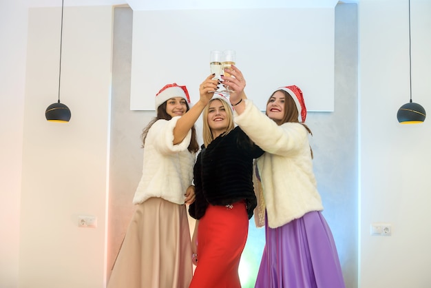 Three attractive women with champagne glasses toasting on party. New year celebration