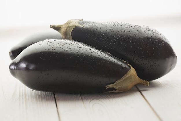 Three aubergines on wooden board