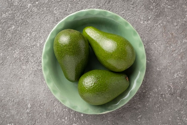 Three avocado fruits in a green plate