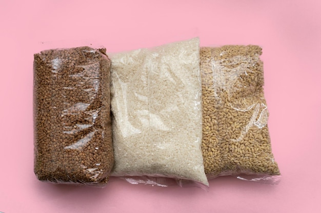 Three bags with groats on a pink background Victim assistance concept Buckwheat rice barley