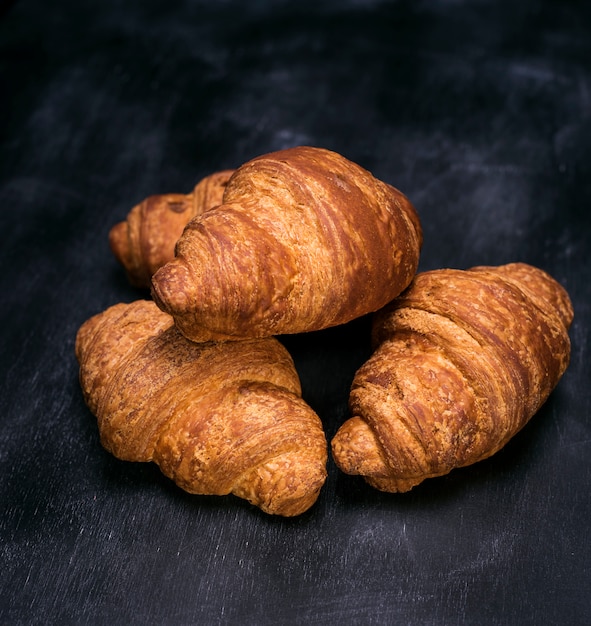 Three baked croissants on black