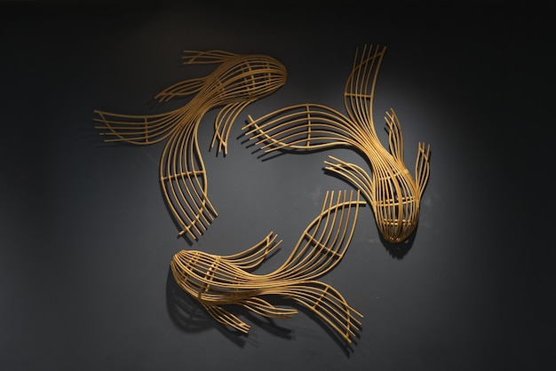 Three bamboo fish like decoration on a black wall