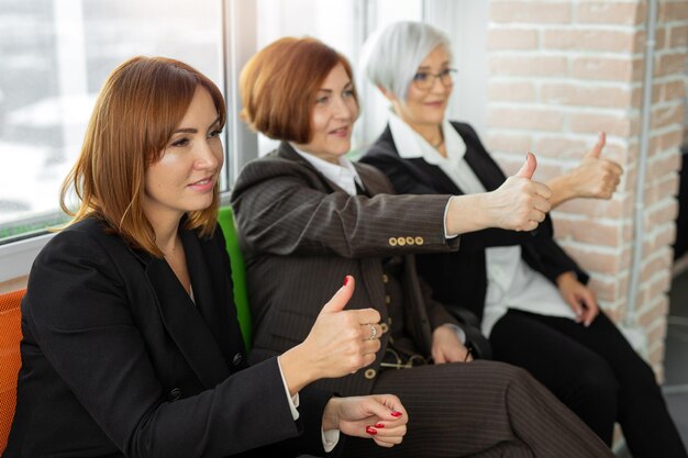 three beautiful adult women in suits with hand gesture