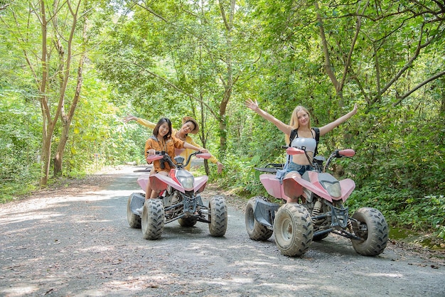 Three beautiful women travel while riding an ATV in forest