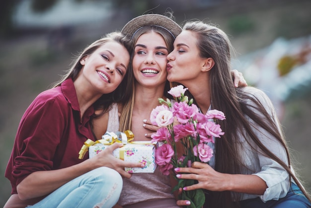 屋外で花を持つ3人の美しい若い女性