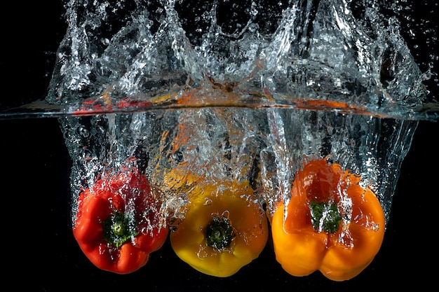 Foto una spruzzata di tre peperoni dolci sull'acqua