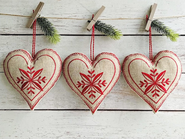 Three big heart wall hanging from linen with red embroidery. Handmade baubles zero-waste Christmas.