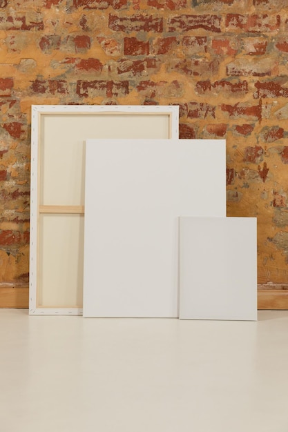 Three blank canvases leaning against a brick wall