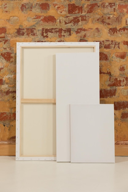 Photo three blank canvases leaning against a brick wall