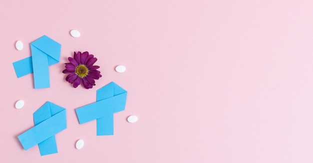 Three blue ribbons gerbera and pills on a pink background