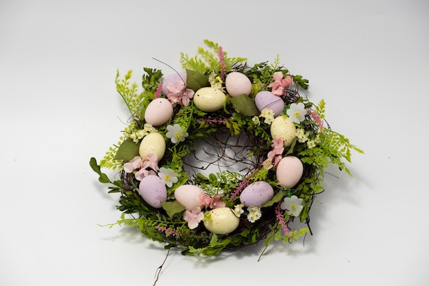 Three blue spotted chicken eggs and a wreath of willow twigs on a white background top view