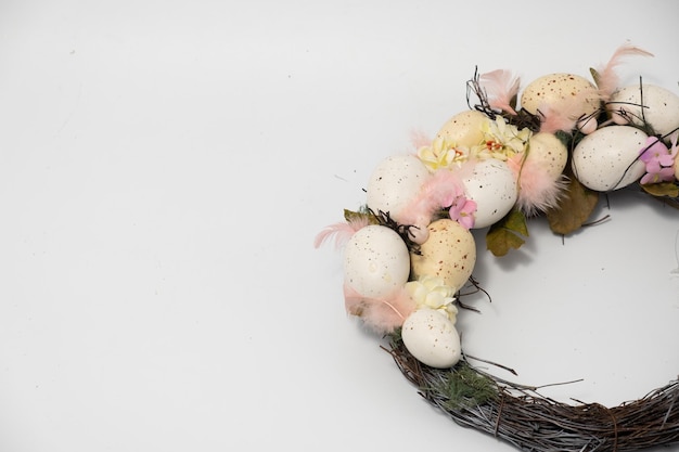 Three blue spotted chicken eggs and a wreath of willow twigs on a white background top view