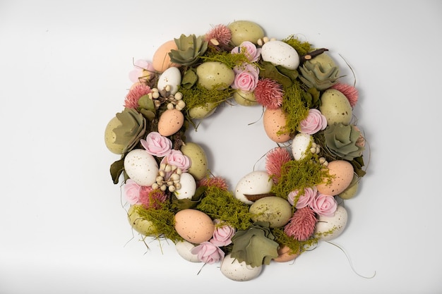 Three blue spotted chicken eggs and a wreath of willow twigs on a white background top view