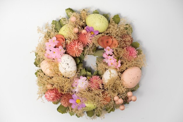 Three blue spotted chicken eggs and a wreath of willow twigs on a white background top view