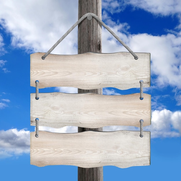 Three boards hanging on post on ropes with sky in background