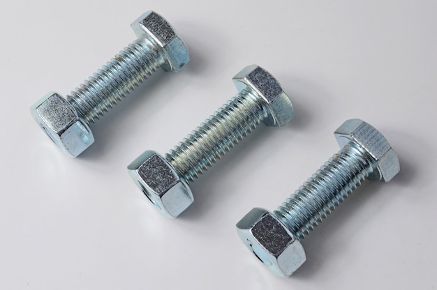 Three bolts with nuts screwed on them. White background.