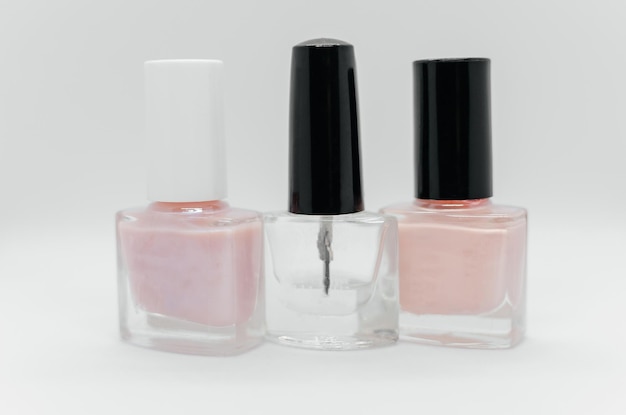 Three bottles of nail polish one of which is pink and the other is pink