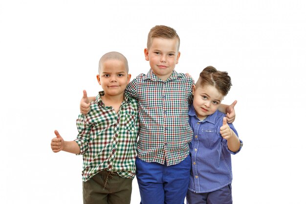 Photo three boys are standing together and hold their thumbs up