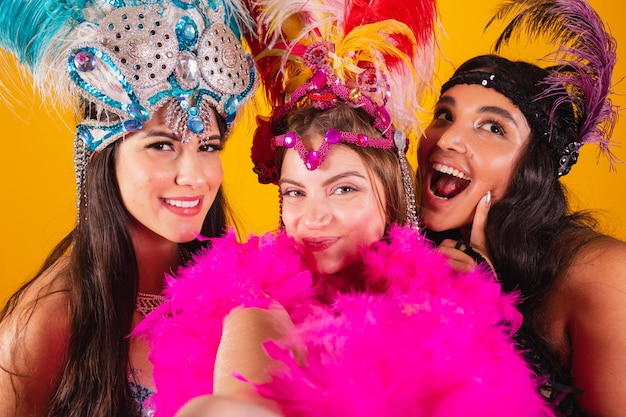 Three brazilian female friends with queen clothes from samba school carnival Feather crown taking self portrait with smartphone