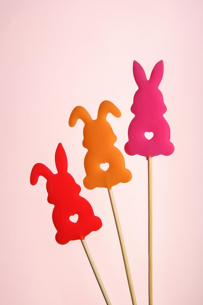 Three bright lollipops in the shape of hares on a pink background banner for Valentines Day