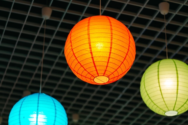 Three brightly colored lanterns hanging from a ceiling