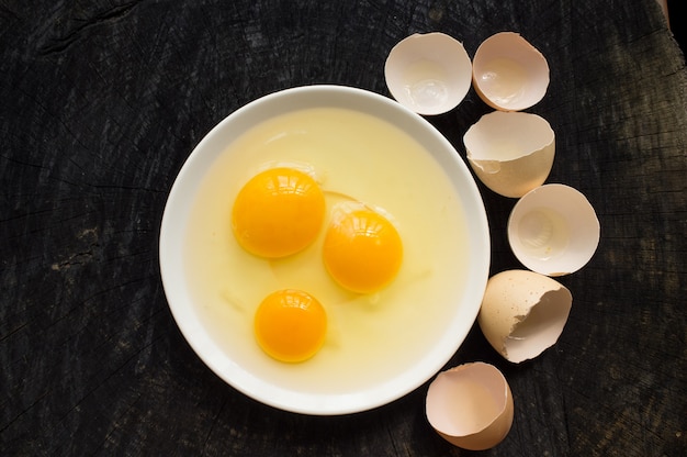 Photo three broken raw eggs on a white plate