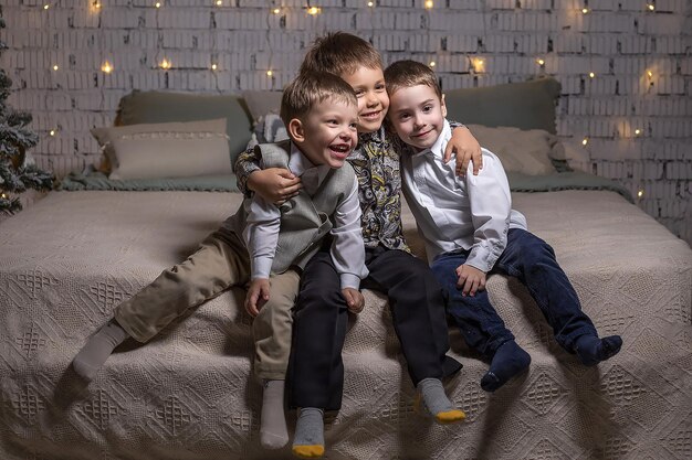 Three brothers are sitting cheerful on the bed and waiting for\
the new year to come