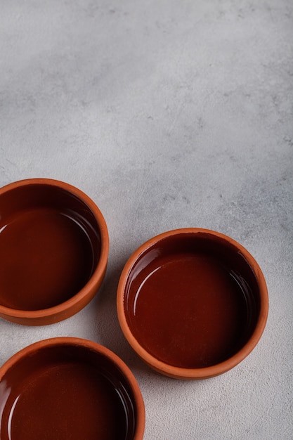 Three brown clay bowls on a light background