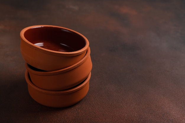 Three brown handmade clay bowls on a dark table