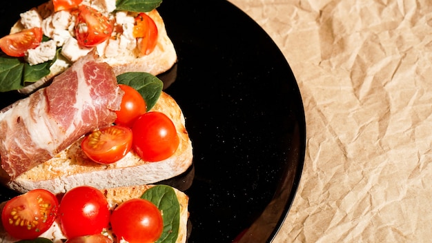 Tre bruschette su banda nera su carta artigianale. antipasto con pomodorini, ricotta, spinaci e pancetta.