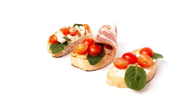 Foto tre bruschette su una ciabatta su un piatto bianco. antipasto italiano su uno sfondo isolato. set con pomodori e pancetta