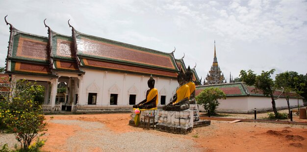 Three Buddha Brother statue beside ubosot and Chedi of Wat Phra Borommathat Chaiya Temple in Chaiya district in Surat Thani Thailand