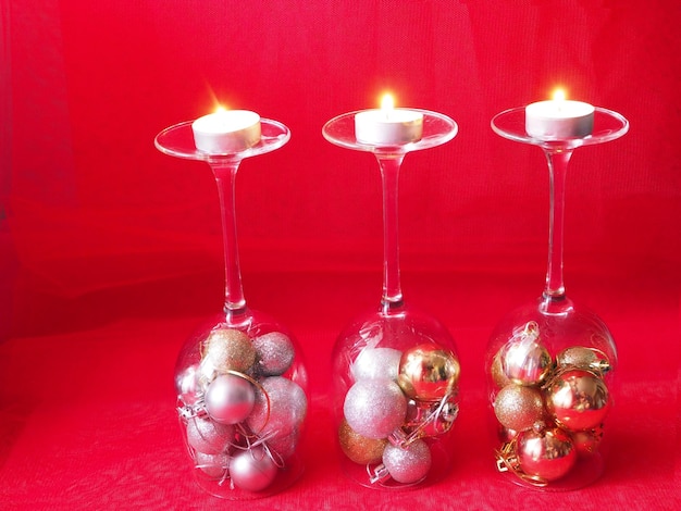 Three burning candles on candlesticks made of wine glasses and Christmas tree balls